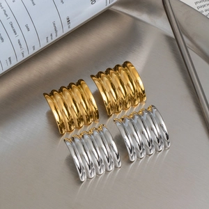 Polished gold and silver wave textured rectangular earrings on a metal tray