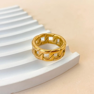 Macro shot of gold cuban link chain ring made of polished stainless steel on white steps
