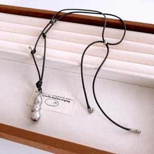 Dettaglio della collana con ciondolo a forma di arachide d'argento su scatola regalo