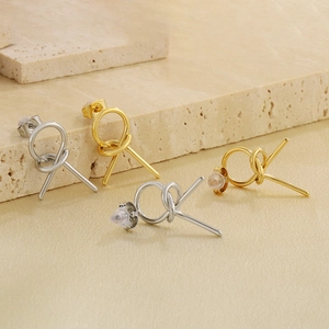 Detail of minimalist knotted hollow geometric earrings in gold and silver finishes