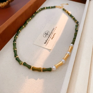 Dettaglio di collana vintage stile bambù con perline verde scuro e perle bianche