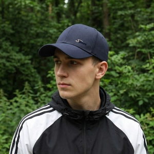 Men's navy blue baseball cap with S Sport embroidery in outdoor forest setting