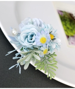 Detailed close-up of light blue rose boutonniere with decorative white pearl and green leaves