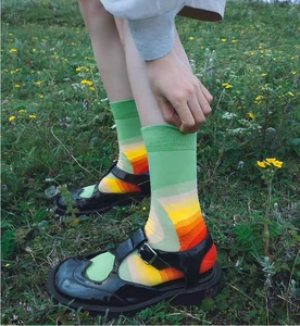 Dettaglio di calze verdi a righe arcobaleno e scarpe Mary Jane in vernice nera
