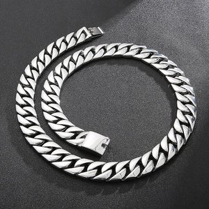 Close-up of polished silver stainless steel Cuban link chain on a textured black background