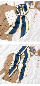Detailed view of striped silk scarf tied in a bow on a beige knitted sweater background