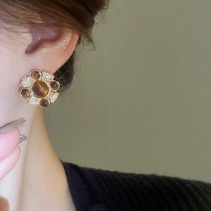 Detail of vintage flower cluster earring featuring brown stones and white pearls on model