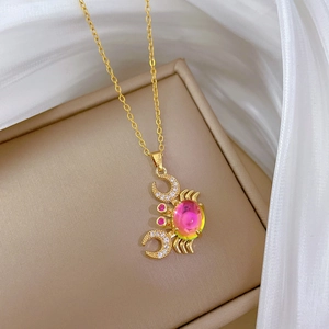 Close-up of golden crab pendant with colorful gradient gemstone and sparkling crystals