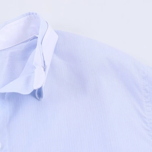 Detail shot of the light blue shirt collar and shoulder showing fine fabric texture