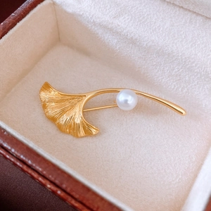 Detail einer 18K vergoldeten Ginkgo-Blatt-Brosche mit Perle in brauner Schmuckschatulle