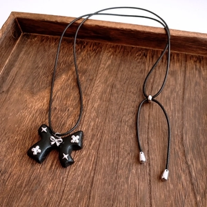 Detail of a black bow necklace with a silver star pendant on a rustic wooden tray