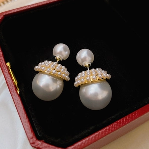 Détail de boucles d'oreilles double perle élégantes sur un écrin à bijoux rouge