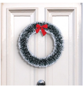 Detail of Christmas tinsel wreath with snow-tipped branches and a red satin bow on a door