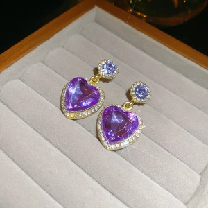 Vue détaillée de boucles d'oreilles cœur violet avec monture dorée sertie de diamants