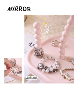 Close-up showing the ball-shaped support and jewelry tray of a cream pink makeup mirror