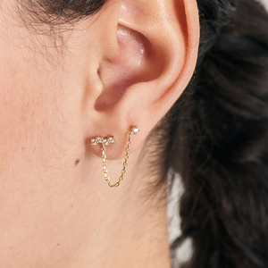 Detail of gold chain earring for double ear piercing featuring opal and zircon stones