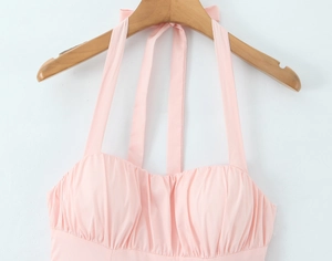 Detail of pink halter neck dress featuring elegant pleated texture and strappy design