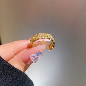 Close-up of gold coin pattern ring with pavé-set zircons and adjustable open band