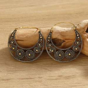 Detail of vintage gold hoop earrings with spiral texture on a rustic wooden stand