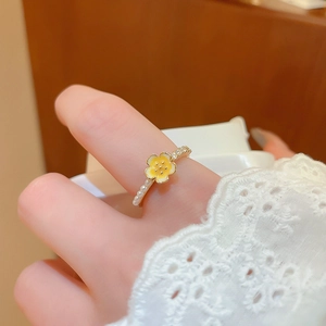 Detail of gold flower ring with white pearls and enamel worn on a female hand
