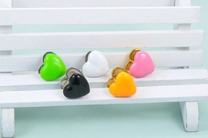 Close-up of five colorful enamel heart earrings on a miniature white bench display
