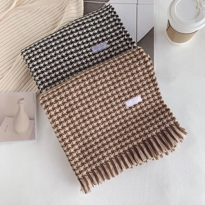 Detail of wool blend houndstooth scarves with fringe edges in black and brown