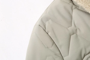 Close-up of light sage quilted jacket with hexagonal patterns and white faux shearling collar