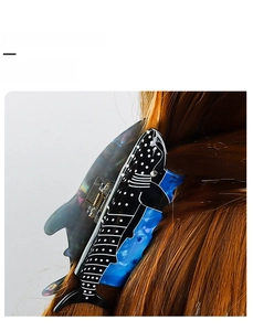 Blue whale-shaped hair claw clip with printed patterns displayed on long brown hair
