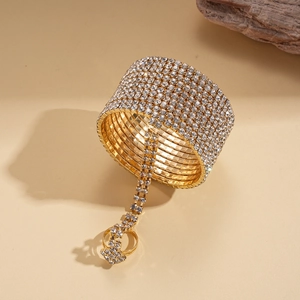 Detail of a gold-plated multi-layer slave bracelet with crystals on a beige surface