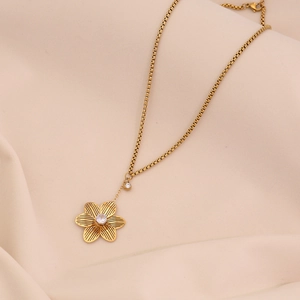 Détail d'un collier pendentif fleur dorée avec cristal clair sur une chaîne gourmette