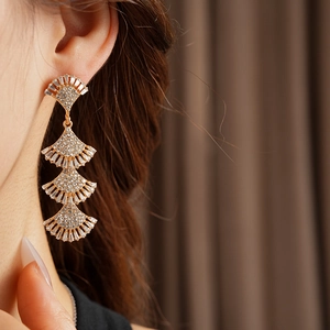 Close-up of elegant gold layered fan fringe earrings with diamonds worn by a model