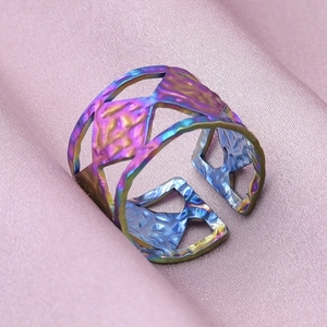 Detailed close-up of rainbow gradient geometric open ring on pink silk fabric