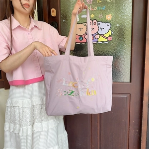 Gros plan sur le sac en toile lavande avec broderie colorée et large bandoulière