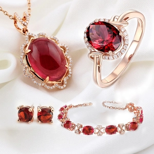 Rose gold jewelry set with pigeon blood ruby stones on white silk background