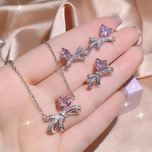 Detail of pink heart zircon jewelry set with silver bow necklace and earrings on model