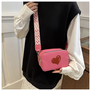 Pink heart print crossbody bag featuring a patterned wide strap and smooth PU texture