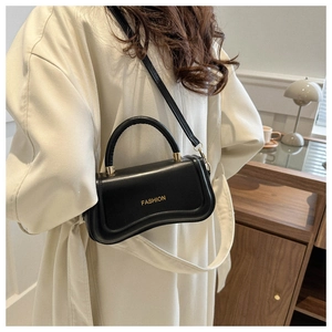 Detail of black leather handbag with unique wavy base design and gold fashion text