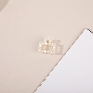 Detail view of square hollow pearl hair claw clip with golden metal spring mechanism