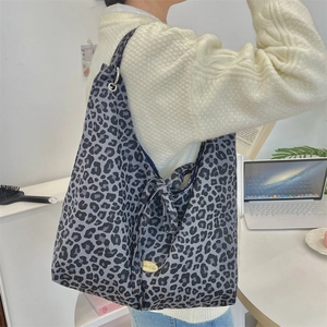 Close-up of leopard print canvas tote bag with knot detail and golden brand logo plate