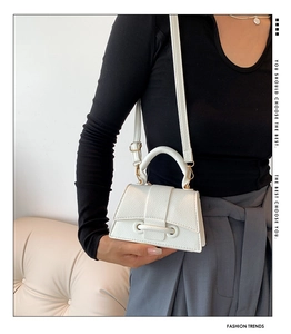 Detail of white mini handbag featuring woven texture and gold hardware on an hourglass base