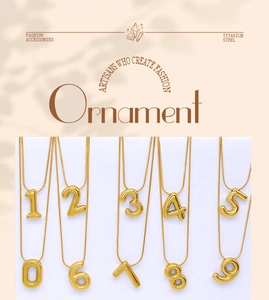 Mise à plat de colliers en acier titane doré avec pendentifs numérotés de 0 à 9