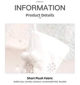 Detail of white plush Christmas stocking with silver snowflake embroidery and pom poms