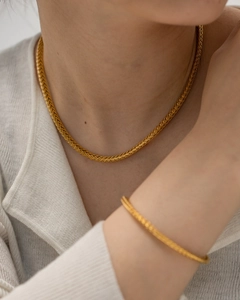 Detail of 18K gold-plated braided chain necklace and bracelet set on a model