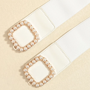Detail view of two white wide elastic belts with gold square pearl-encrusted buckles