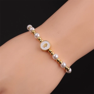 Detail of Fatima Hand bracelet featuring white pearls and golden beads on model wrist