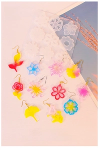Flat lay of colorful resin earrings made with floral silicone molds on a pink background