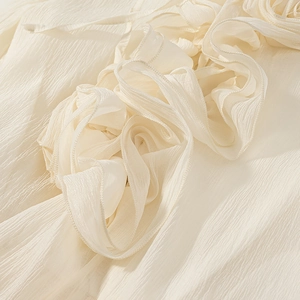 Macro detail of cream pleated fabric with elegant 3D floral accents and soft texture