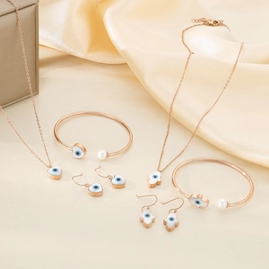 Rose gold jewelry set with devil's eye heart and hand motifs on silk fabric background