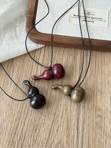 Macro detail of three handmade wooden gourd pendants in dark red, black, and green finishes
