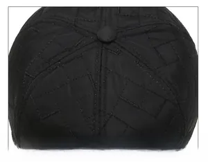 Detailed macro view of black quilted crown stitching and top button on a winter baseball cap